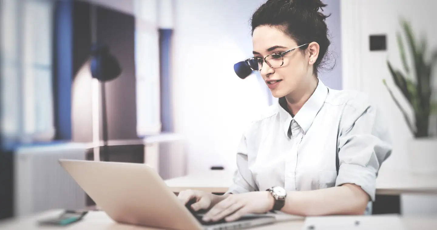 Eine Steuerberaterin sitzt in ihrem Büro und informiert eine Klientin per Mail über ihren Steuerbescheid.