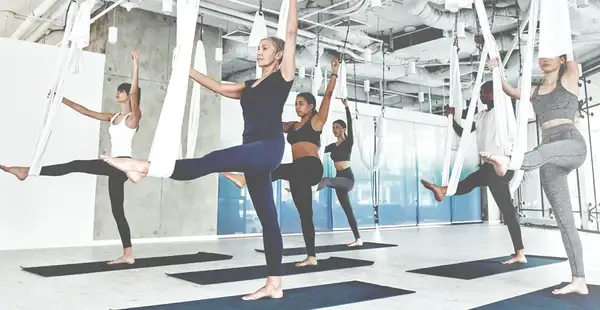 Eine Gruppe Frauen macht Seilyoga in einem Trainingsraum.