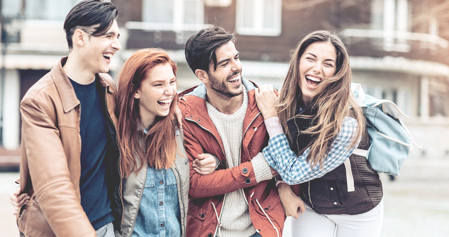 Eine Gruppe junger Student*innen flanieren lachend über den Campus.