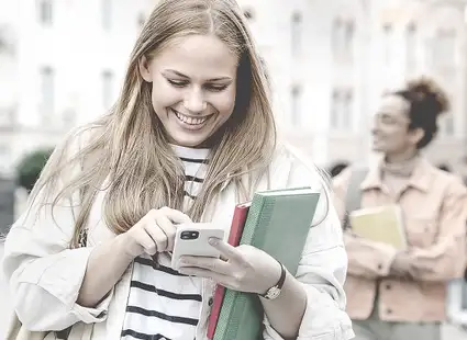 Eine junge Frau checkt am Smartphone ihre E-Mails und findet heraus, dass sie eine Zusage für ein Stipendium bekommen hat.