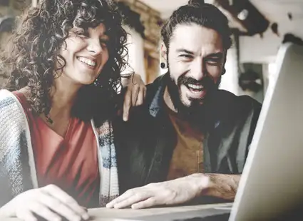 Eine Frau und ein Mann sitzen vor einem Laptop und informieren sich über das Thema Studienbewerbung.