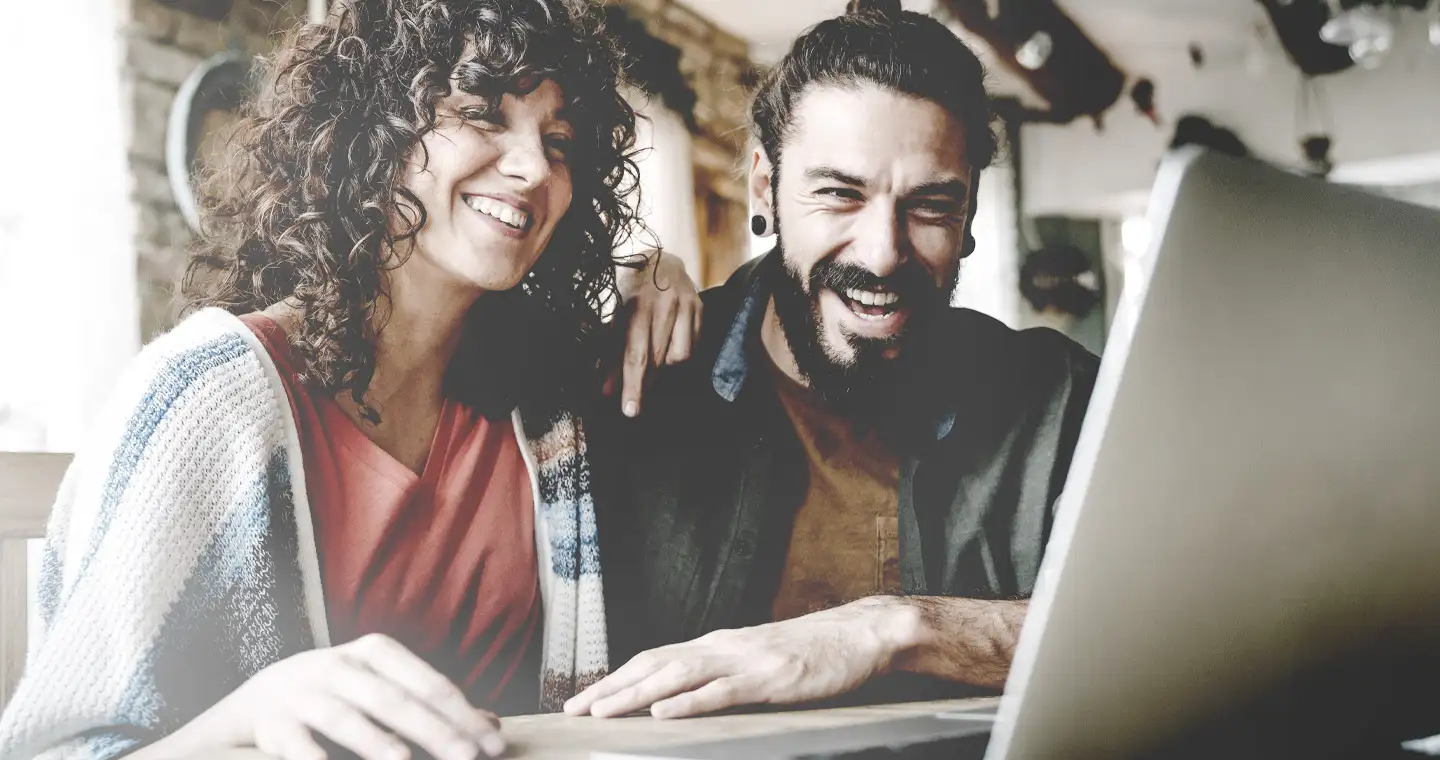 Eine Frau und ein Mann sitzen vor dem Computer und schreiben gemeinsam eine Studienbewerbung.