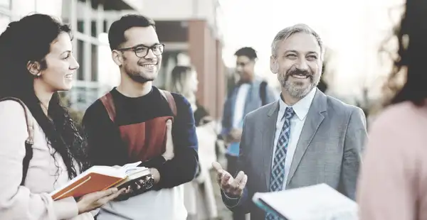 Masterstudierende reden mit ihrem Professor auf dem Campus