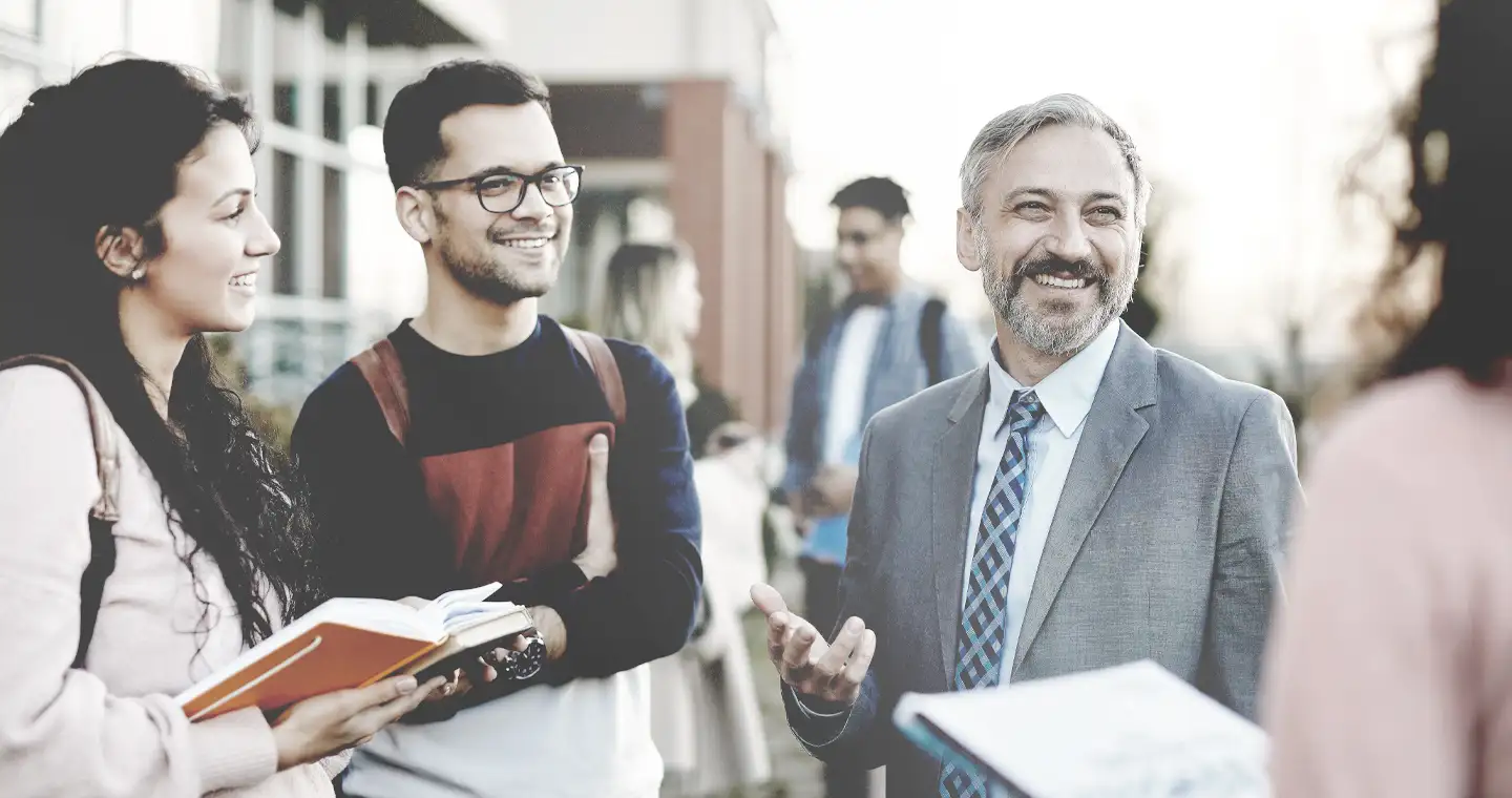 Drei Masterstudenten im Gespräch mit einem Professor. 