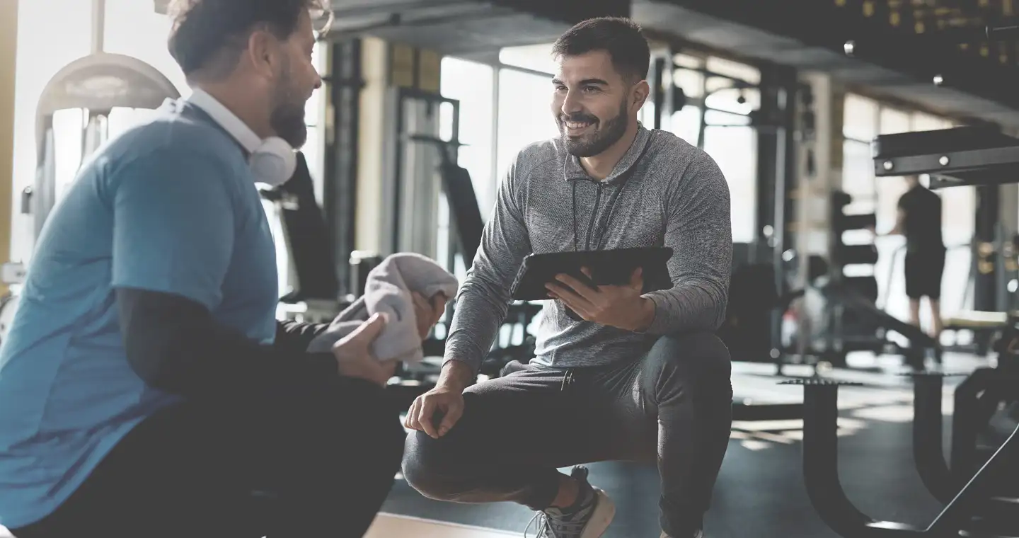 Ein Sportwissenschaftler berät einen Klienten im Fitnessstudio.