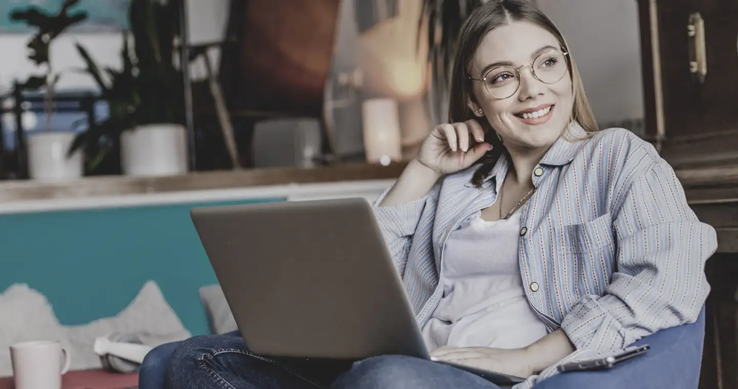 Eine junge Frau informiert sich an ihrem Laptop über das Wirtschaftspsychologiestudium.