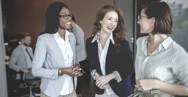 Junge Frauen lachen gemeinsam, nachdem sie an einem Vorbereitungskurs für die Steuerberaterprüfung teilgenommen haben.