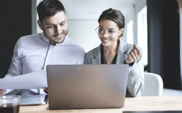 Zwei Masterstudenten der Sozialwissenschaften diskutieren über Forschungsdaten und Ergebnisse auf einem Laptop.