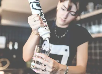 Studentin hat einem Nebenjob in einem Café und dekoriert ein Kaffeeglas..