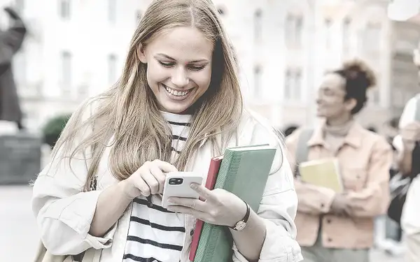 Eine junge Frau checkt am Smartphone ihre E-Mails und findet heraus, dass sie eine Zusage für ein Stipendium bekommen hat.