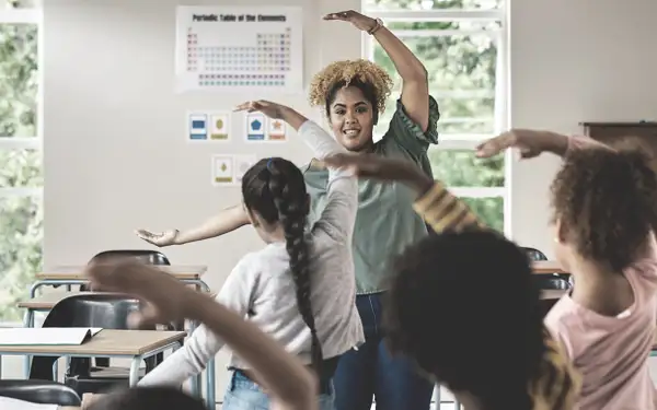 Eine Inklusionspädagogin leitet eine Gruppe von Kindern in einem Klassenzimmer bei einer gemeinsamen Aktivität an.