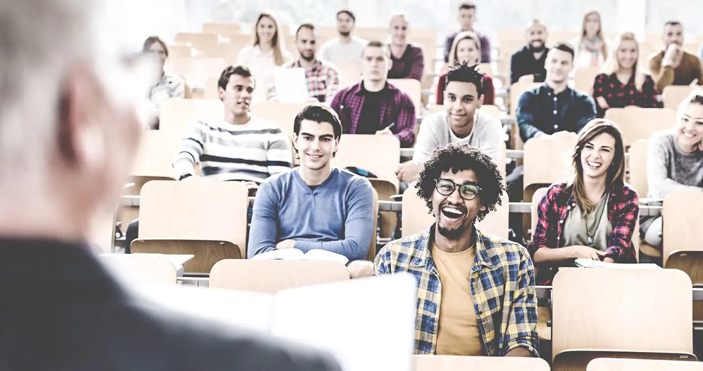 Eine große Gruppe Studierender hört in einem Hörsaal einem Dozierenden zu.