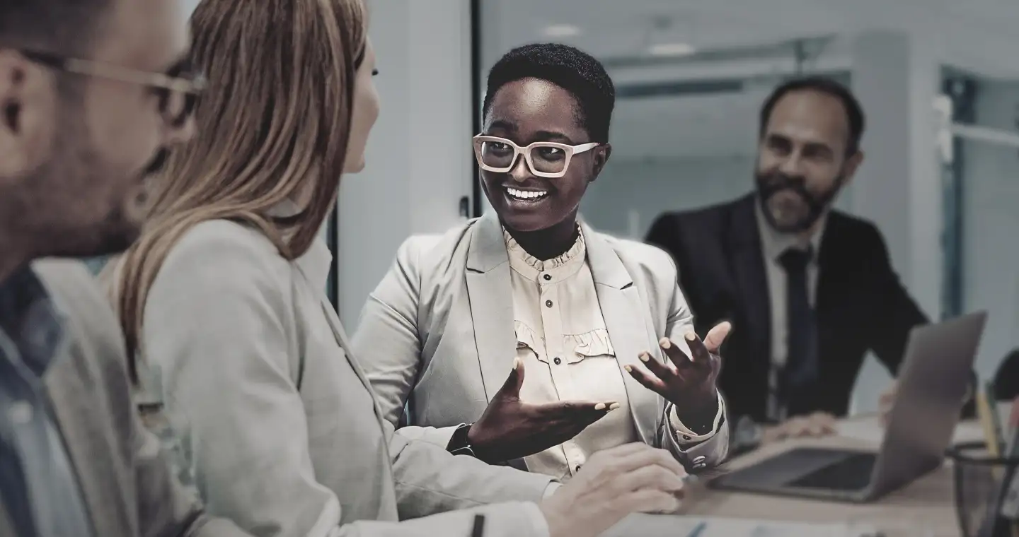 Eine Personalentwicklerin sitzt mit Geschäftsleuten in einem Meeting und erläutert eine Strategie.