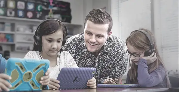 Ein Bildungswissenschaftler lernt mit Kindern, die ein Tablet in der Hand halten. 