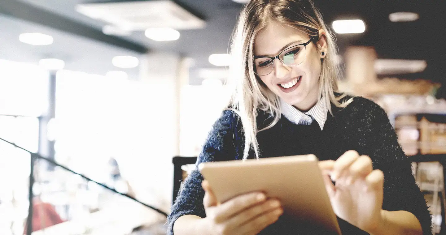 Junge Studentin sitzt in einem Café und lernt am Tablet.