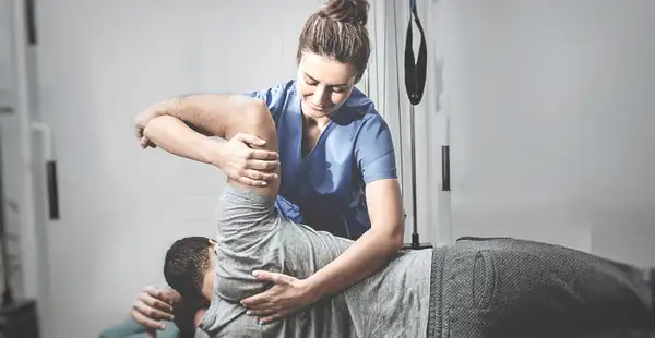 Reha-Trainerin behandelt jungen Sportler nach einer Verletzung.