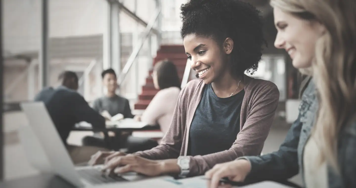 Zwei Abiturientinnen informieren sich an einem Laptop zur Ausbildung als Steuerfachangestellte.