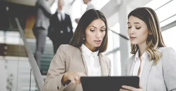 Zwei Pflegemanagerinnen kontrollieren am Laptop Geschäftszahlen.