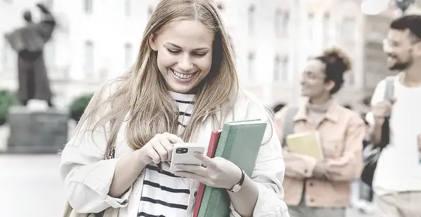 Eine junge Frau checkt am Smartphone ihre E-Mails und findet heraus, dass sie eine Zusage für ein Stipendium bekommen hat.