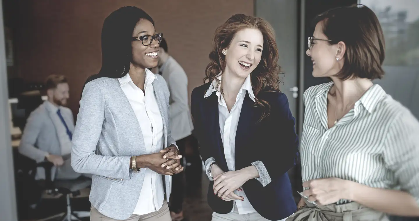 Junge Frauen lachen gemeinsam, nachdem sie an einem Vorbereitungskurs für die Steuerberaterprüfung teilgenommen haben.