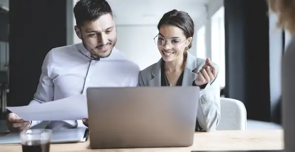 Zwei Masterstudenten der Sozialwissenschaften diskutieren über Forschungsdaten und Ergebnisse auf einem Laptop.