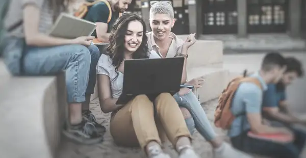 Zwei Studierende nehmen mit ihrem Laptop an einer Umfrage teil.