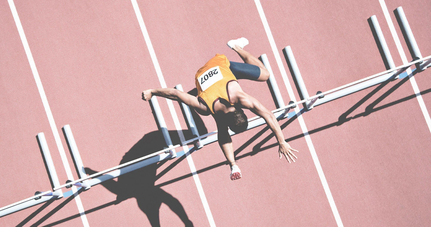 Eine Sportlerin springt über eine Hürde.
