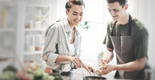 Zwei Ernährungsberater unterhalten sich beim Kochen über die Kosten einer Ausbildung oder eines Studiums zum Ernährungsberater. 