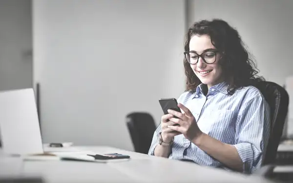 Eine junge Frau recherchiert an ihrem Smartphone, wie die Bestellung zum Steuerberater abläuft.