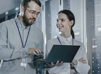 Zwei junge Informationstechniker*innen arbeiten in einem Serverraum.