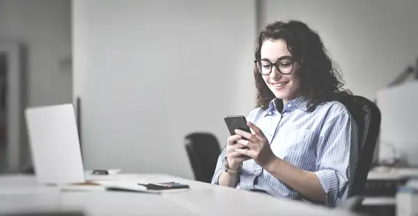 Eine junge Frau recherchiert an ihrem Smartphone, wie die Bestellung zum Steuerberater abläuft.