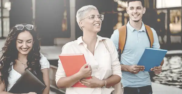 Studieninteressierte laufen mit Broschüren zum Personalmanagement Studium über den Campus