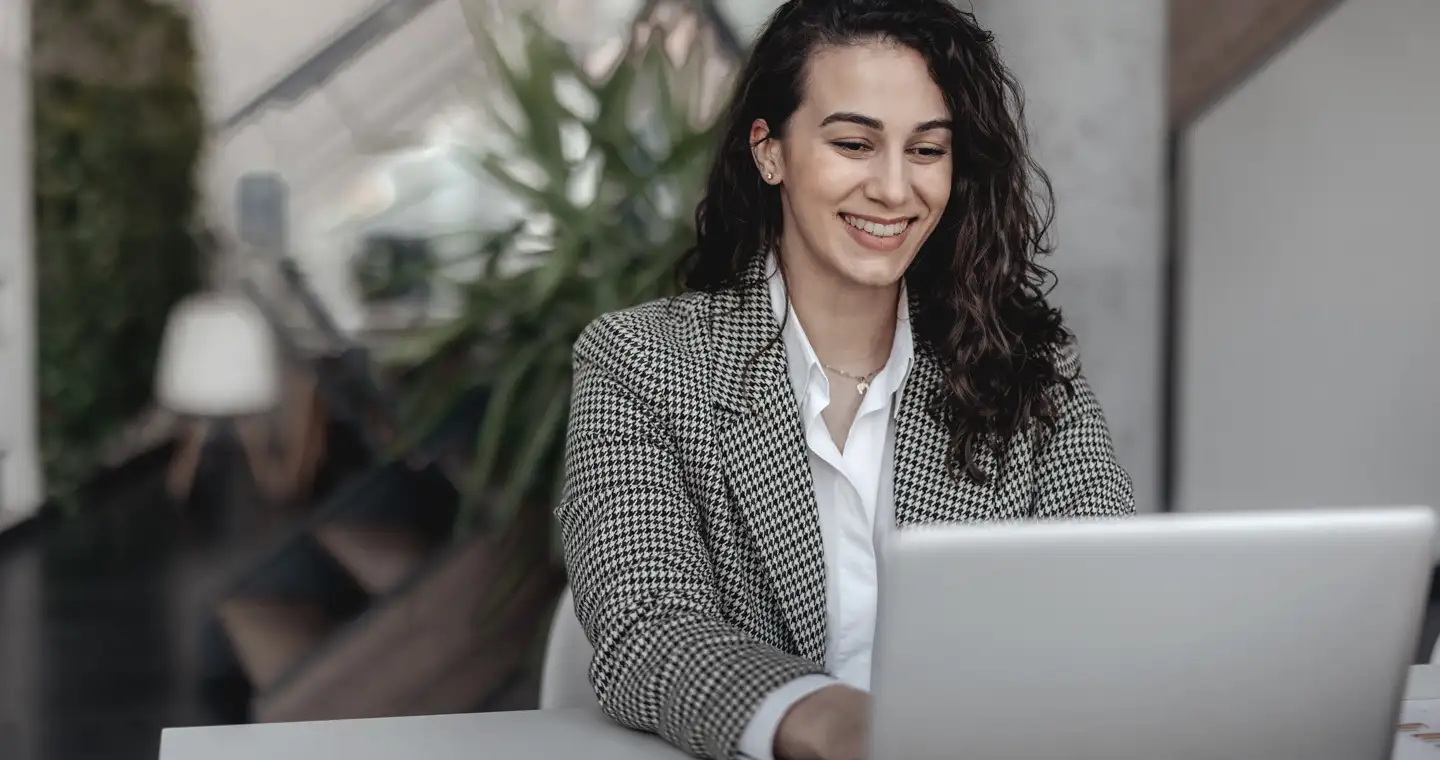 Eine Managerin sitzt vor ihrem Laptop und sieht sich die aktuelle Entwicklung eines Fitnessstudios an.