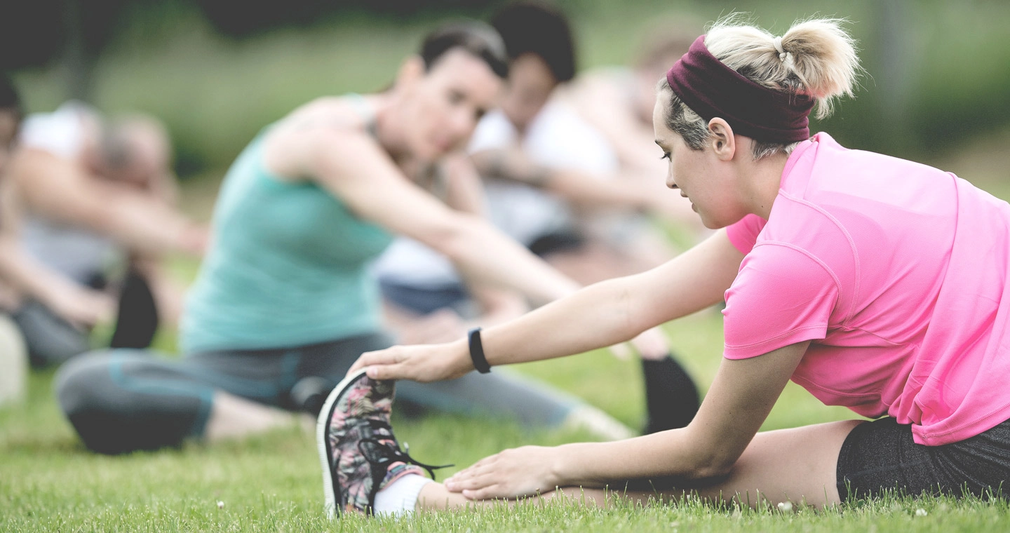 Eine Gruppe junger Sportler*innen macht Yoga im Freien.