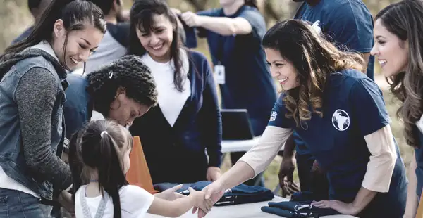 Eine Gruppe von Frauen, die eine Weiterbildung im Bereich Soziales absolviert, arbeitet gemeinsam an einem Infostand im Freien.