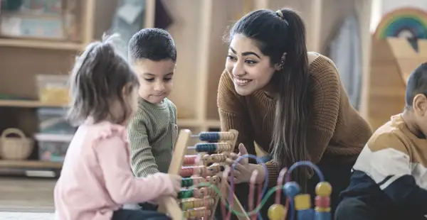 Eine Absolventin des Masterstudiengangs Pädagogik spielt mit Kleinkindern.