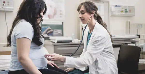 Eine Hebamme, die ein Fernstudium absolviert hat, untersucht eine schwangere Frau in einer Klinik. 