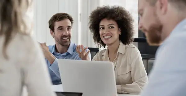 Eine junge Change Managerin sitzt mit ihrem Team in einer Besprechung.