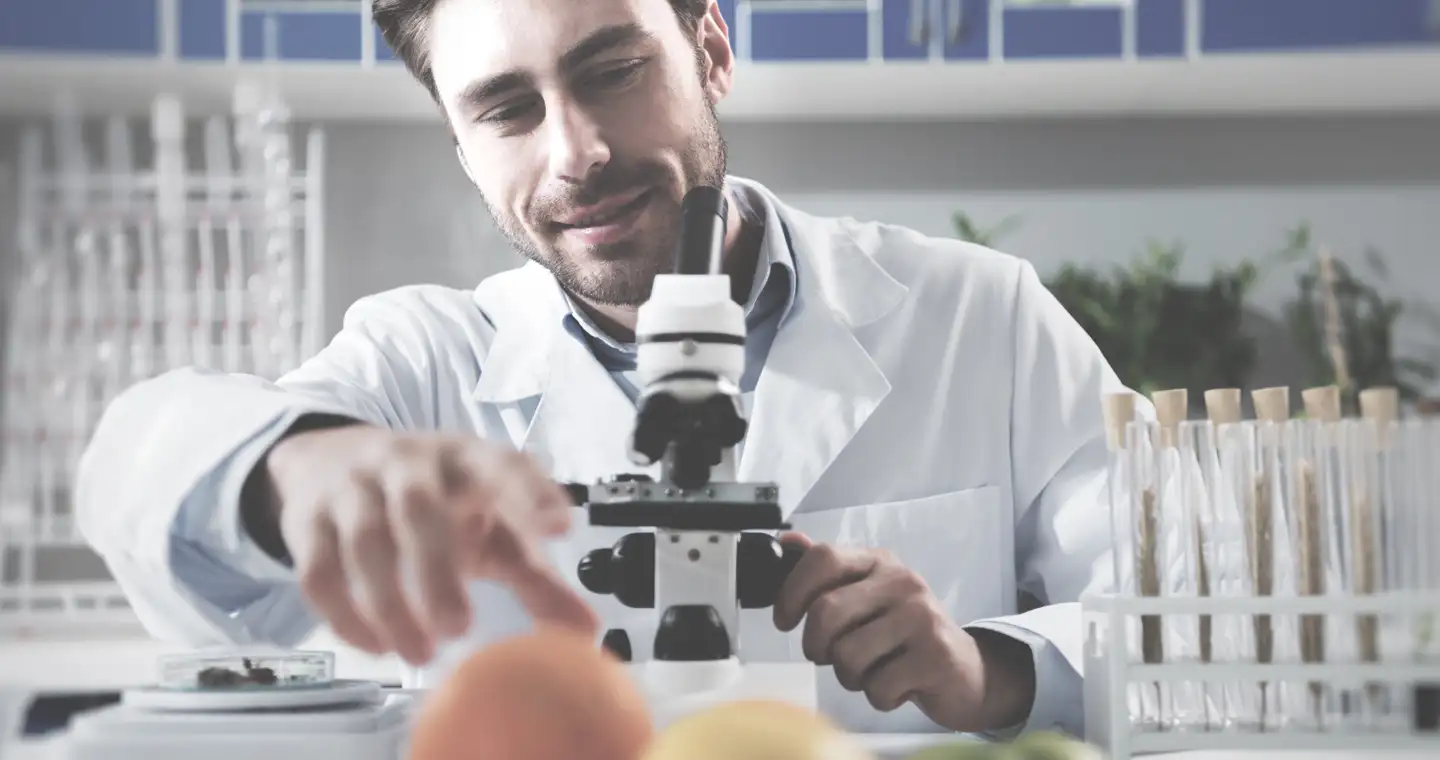 Ein Ernährungswissenschaftler arbeitet in einem Büro am Mikroskop.