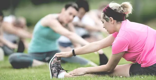 Sportstudierende machen Yoga auf einer Wiese.