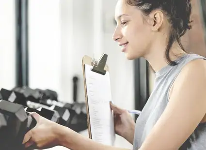 Junge Fitnessökonomin überprüft Geräte in ihrem Fitnessstudio.