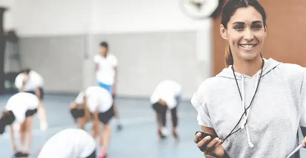 Junge Sportlehrerin betreut ihre Schüler in der Sporthalle