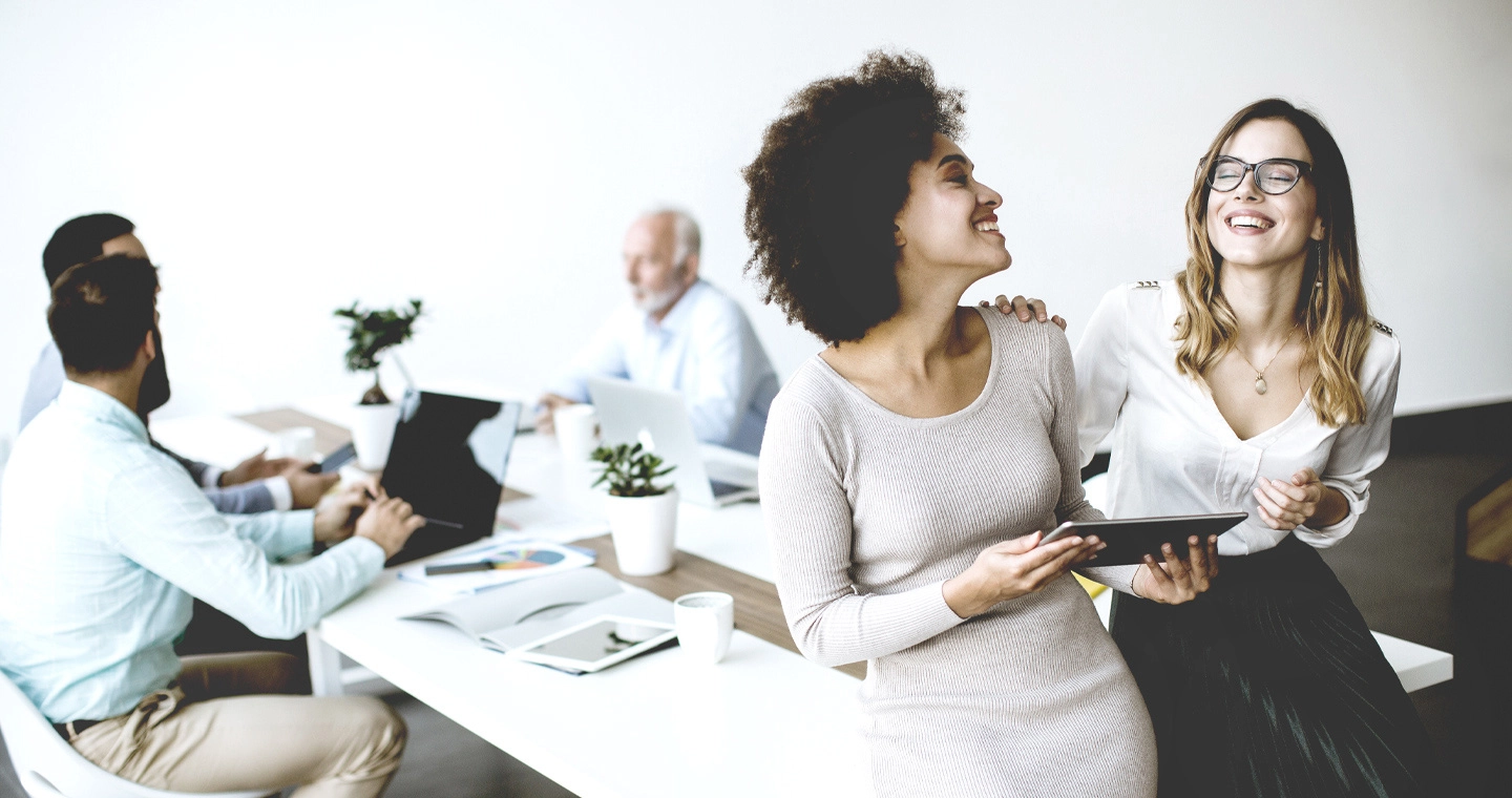 Zwei junge Sport- und Eventmanagerinnen tauschen sich mit Spaß im Büro aus.