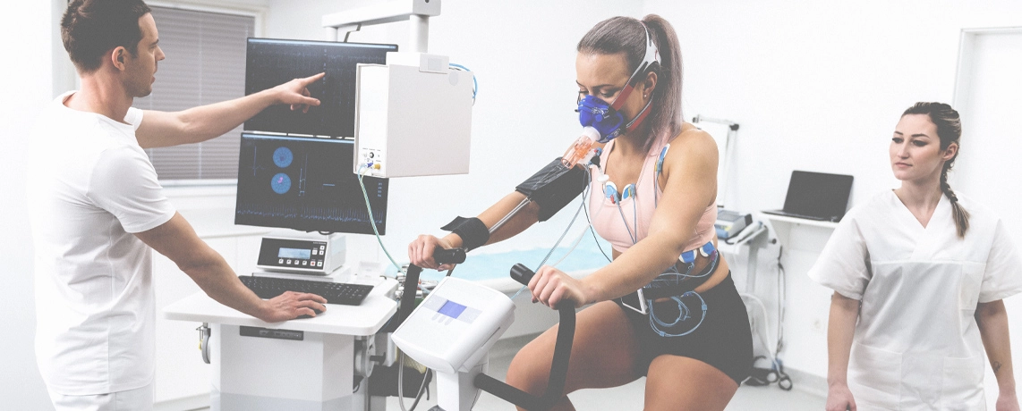 Junge Sportlerin bei sportmedizinischem Test auf einem Ergometer.