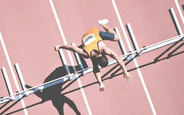 Sportlerin springt über Hürde.