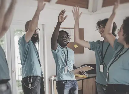 Eine Gruppe junger Sozialarbeiter*innen geben einander ein Highfive.
