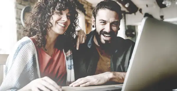 Eine Frau und ein Mann sitzen vor einem Laptop und informieren sich über das Thema Studienbewerbung.