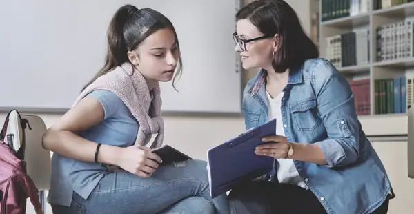 Eine Schulpsychologin spricht einfühlsam mit einer Schülerin und bietet ihr Unterstützung und Rat an.