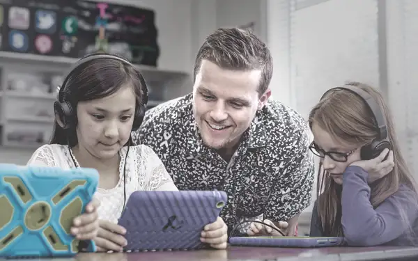 Ein Bildungswissenschaftler lernt mit Kindern, die ein Tablet in der Hand halten. 