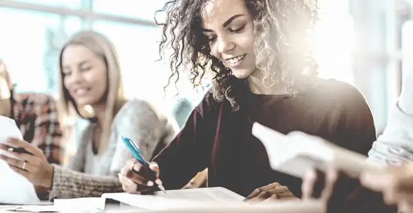 Student*innen für den Wirtschaftsprüfer lernen lächelnd im Hörsaal.